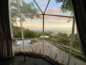 A room with a large window offering a view of a pool and surrounding greenery. - El Mirador (Miramar)