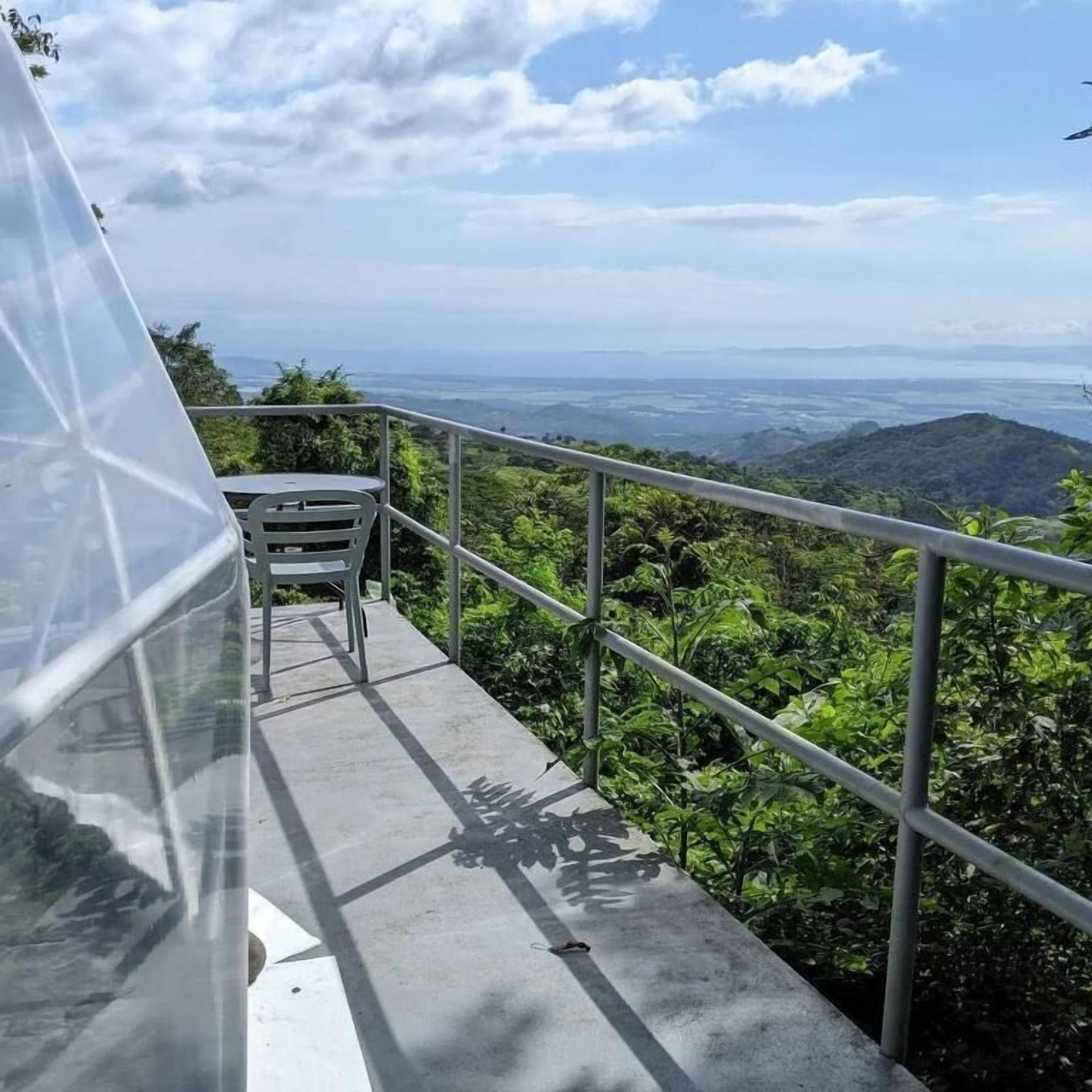 A balcony with a metal railing overlooking a lush green landscape.