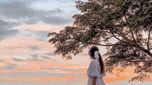 A person standing by a reflective pool with a view of a sunset and distant landscape. - El Mirador (Miramar)