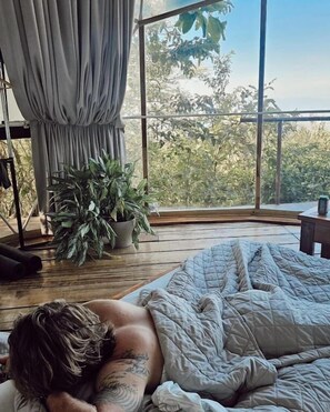 A bedroom with a large window, a bed, a potted plant, and a curtain. - El Mirador (Miramar)
