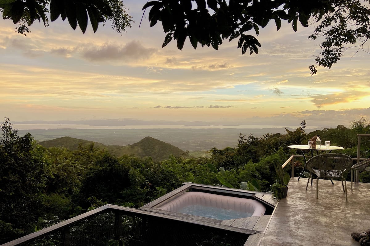 Un jacuzzi con vistas a un paisaje montañoso y una mesa con sillas.