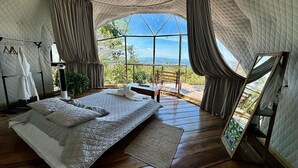A spacious tented room with a large bed, a wooden floor, and a view of the outdoors. - El Mirador (Miramar)