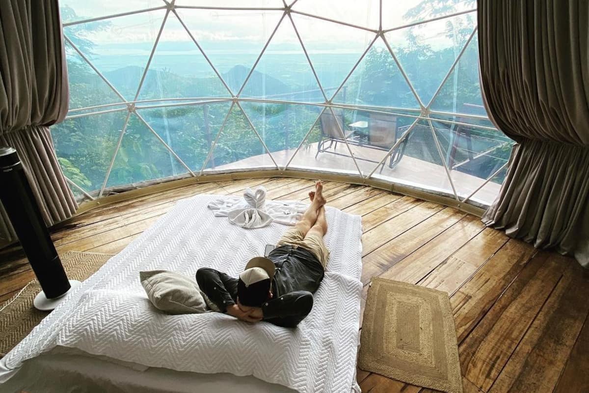 Una habitación con cama, una mesa y vistas por un amplio ventanal.