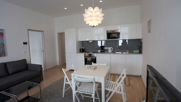 Eine moderne Wohnung mit Essbereich, Küchenzeile und Wohnzimmer mit Sofa und Couchtisch.