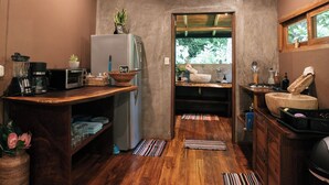 Une cuisine compacte avec un plancher en bois, un ventilateur de plafond, un réfrigérateur et un petit évier.