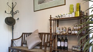 Una habitación acogedora con un banco de madera, un perchero en la pared, un estante con botellas y frascos, y un cuadro enmarcado.