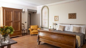 Un dormitorio con cama de madera, una silla, una mesa con un jarrón de flores y un armario.