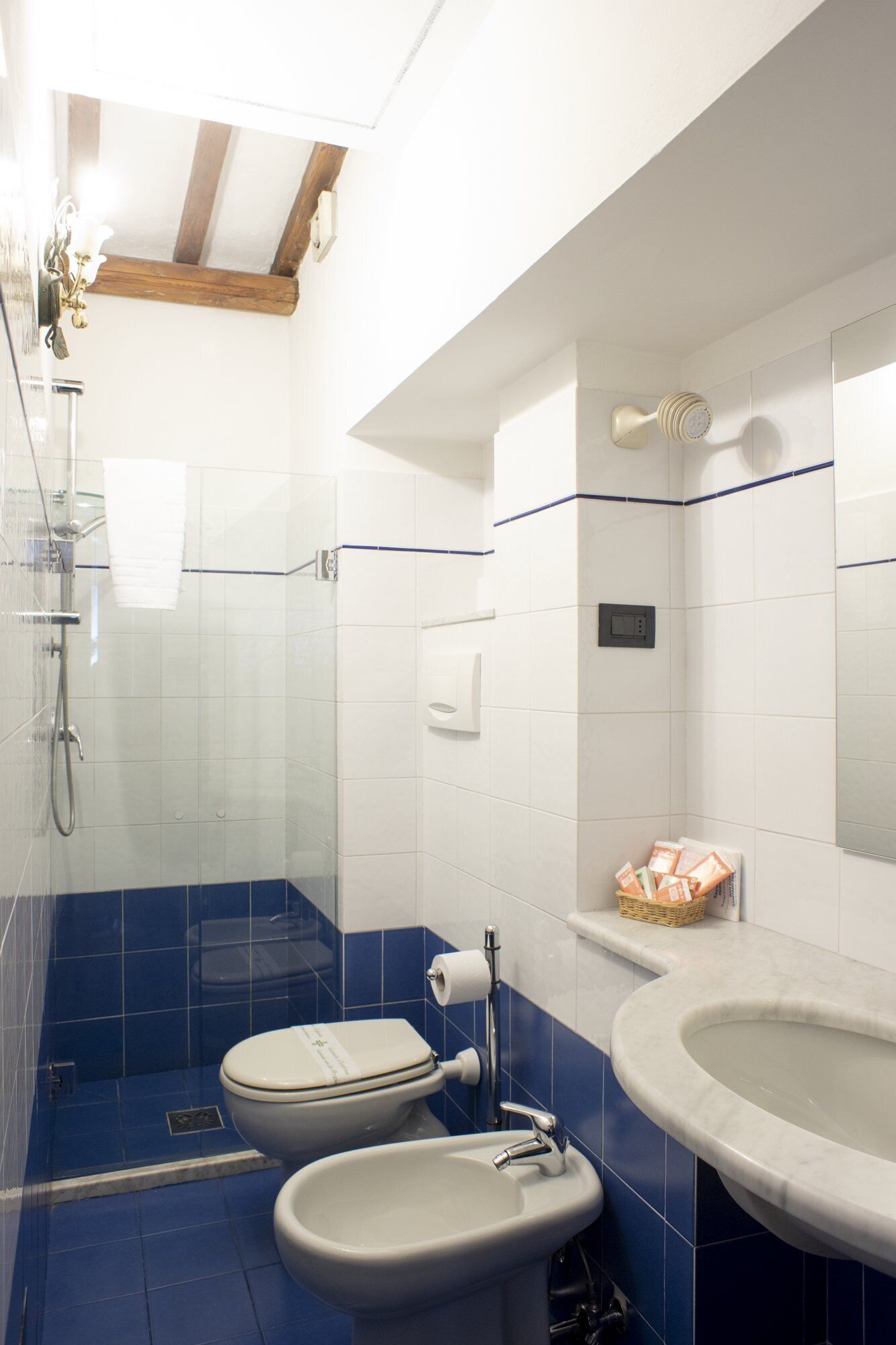 Un baño con ducha, dos inodoros, un lavamanos y una bañera.