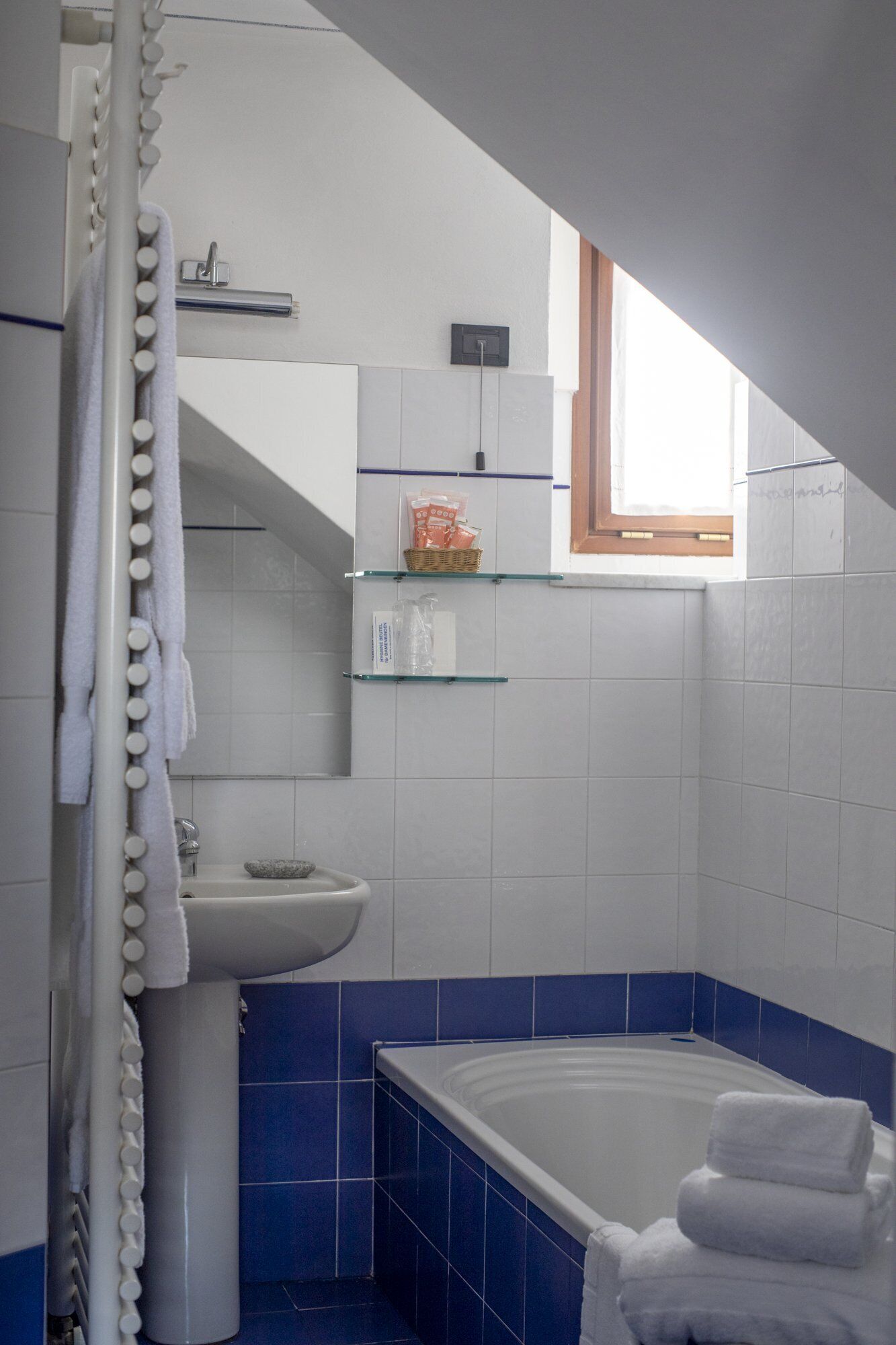 Un baño con bañera, lavabo y cortina de ducha. Una ventana proporciona luz natural.