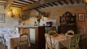 Un comedor con mesas dispuestas para dos, una zona de bar con mostrador y una cocina al fondo.