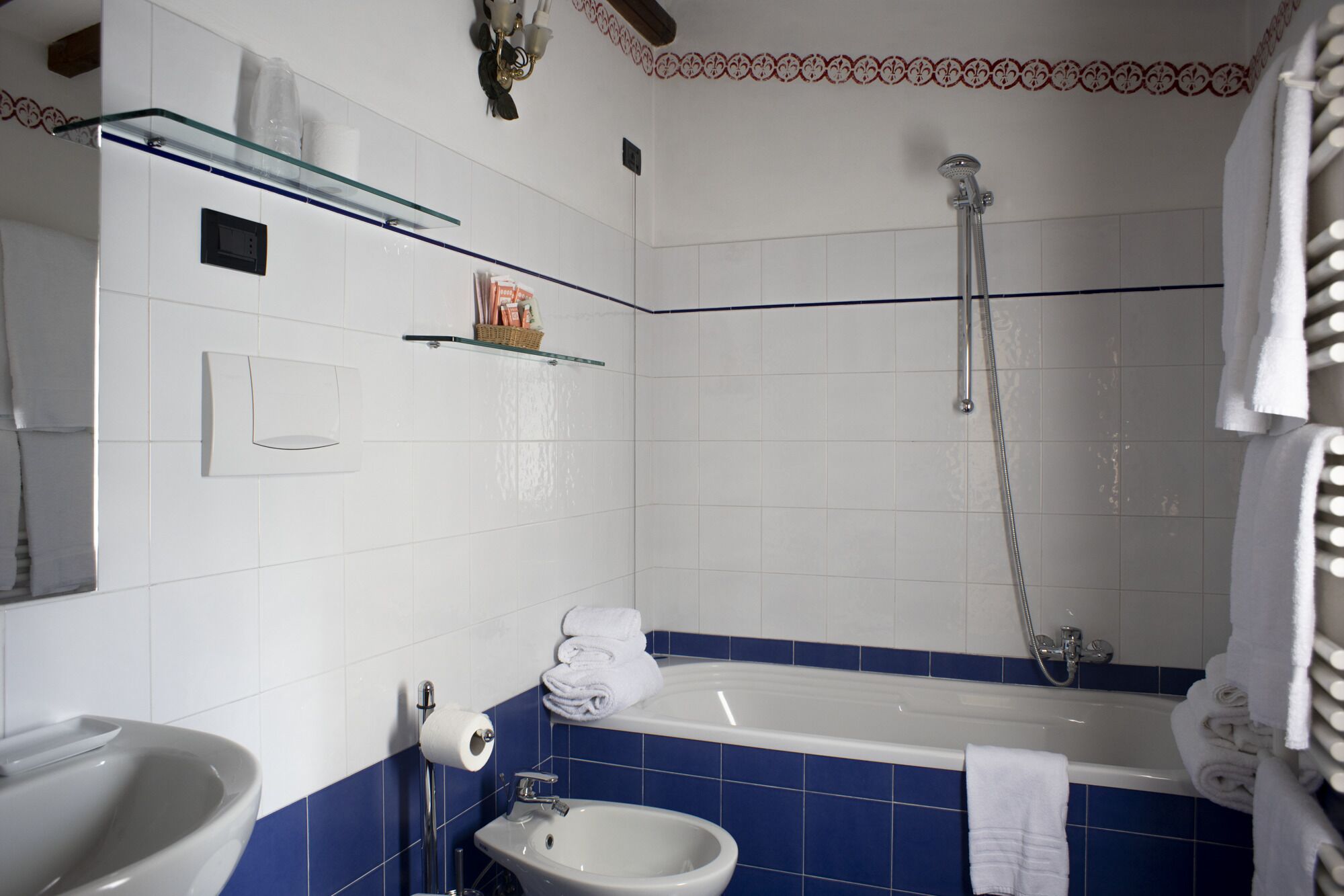 A bathroom with a bathtub, a sink, and a toilet. There is a showerhead above the bathtub and a towel rack with towels.