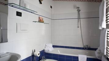 A bathroom with a bathtub, a sink, and a toilet. There is a showerhead above the bathtub and a towel rack with towels.