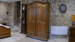 A bedroom with a wooden bed, a wardrobe, a nightstand, and a wall clock.