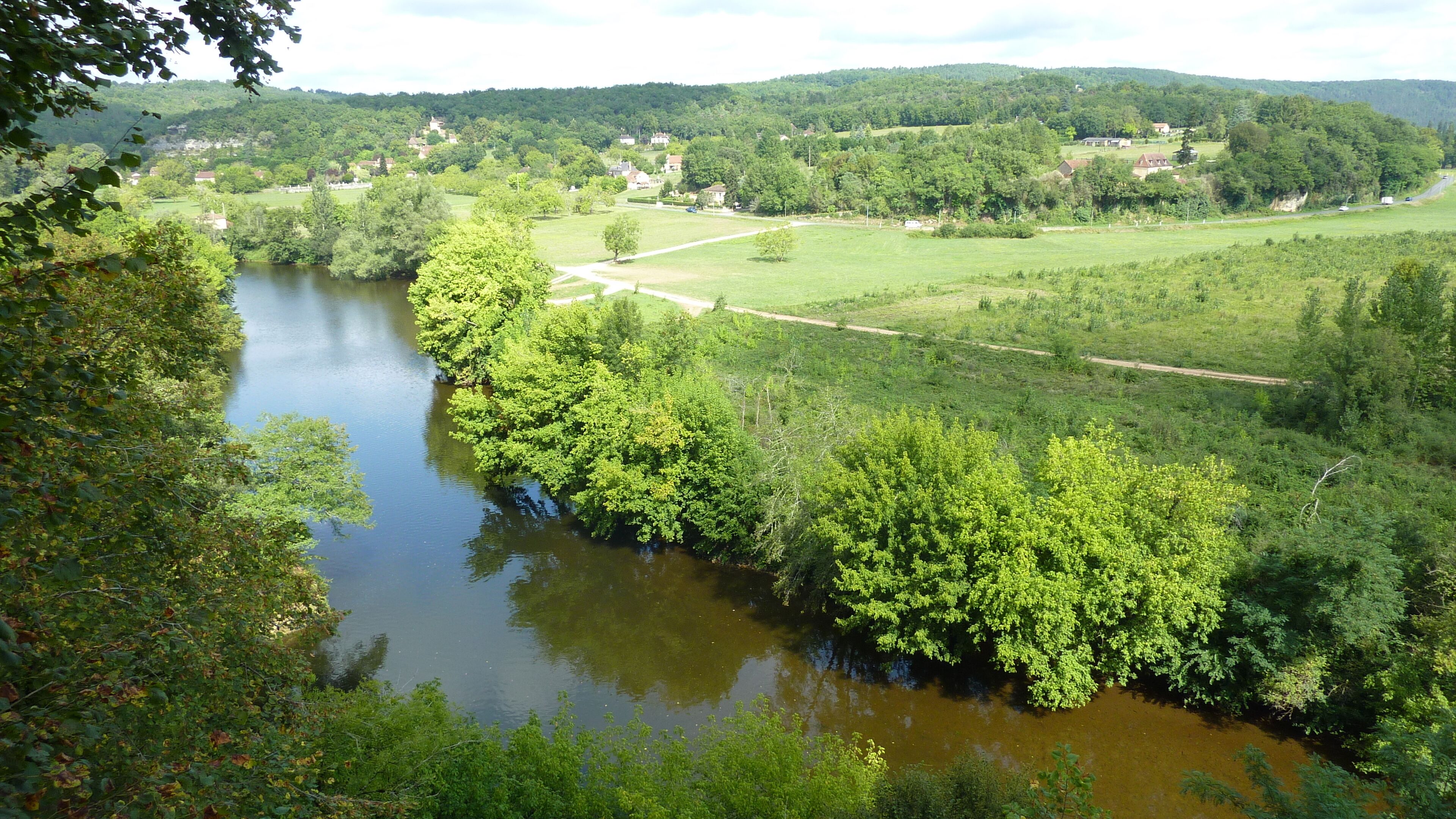 A river winding through a lush green landscape with a road running alongside it.