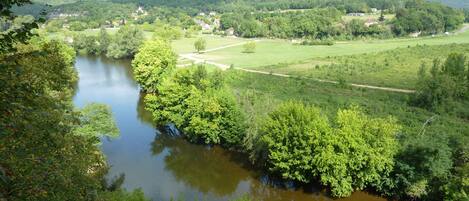 A river winding through a lush green landscape with a road running alongside it.