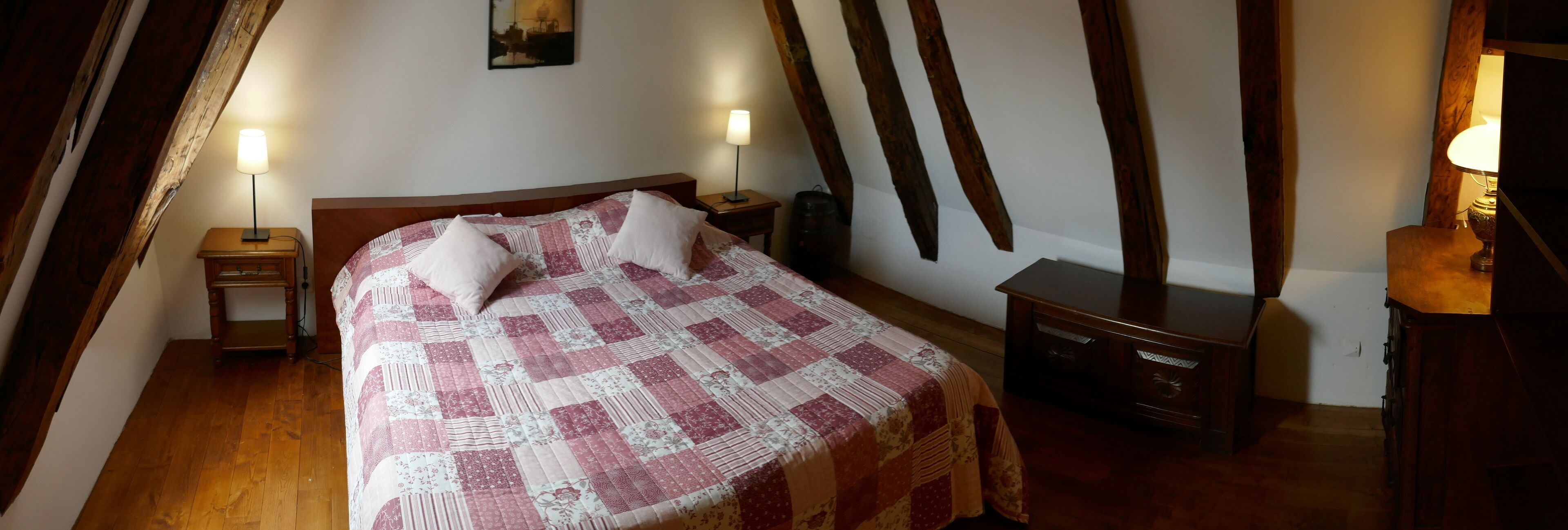 Une chambre à coucher avec un lit en bois, deux tables de chevet, une commode, une commode en bois et une lampe.
