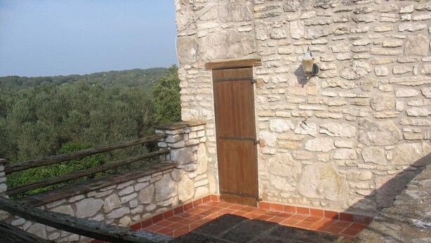 A stone building with a wooden door, a stone staircase, and a view of the surrounding landscape. - Charming villa in the heart of the maquis          (Bonifacio)
