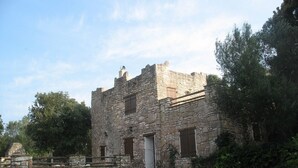 A stone building with a rustic appearance, featuring multiple windows and a wooden door. - Charming villa in the heart of the maquis          (Bonifacio)