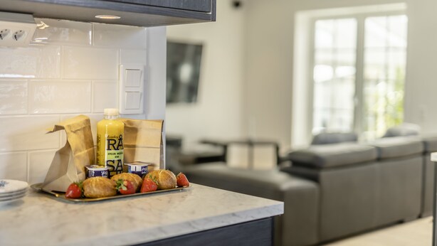 A modern kitchen with a marble countertop, a bottle of juice, and pastries. - Business Home Club (Lidköping)