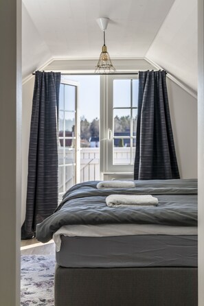 A bedroom with a large bed, a view through a window, and a ceiling light fixture. - Business Home Club (Lidköping)