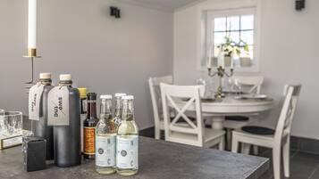 A dining area with a table set for two, featuring a candle, bottles of beverages, and a glass.