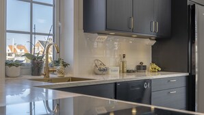 A modern kitchen with dark cabinets, a stainless steel refrigerator, and a marble countertop. - Business Home Club (Lidköping)