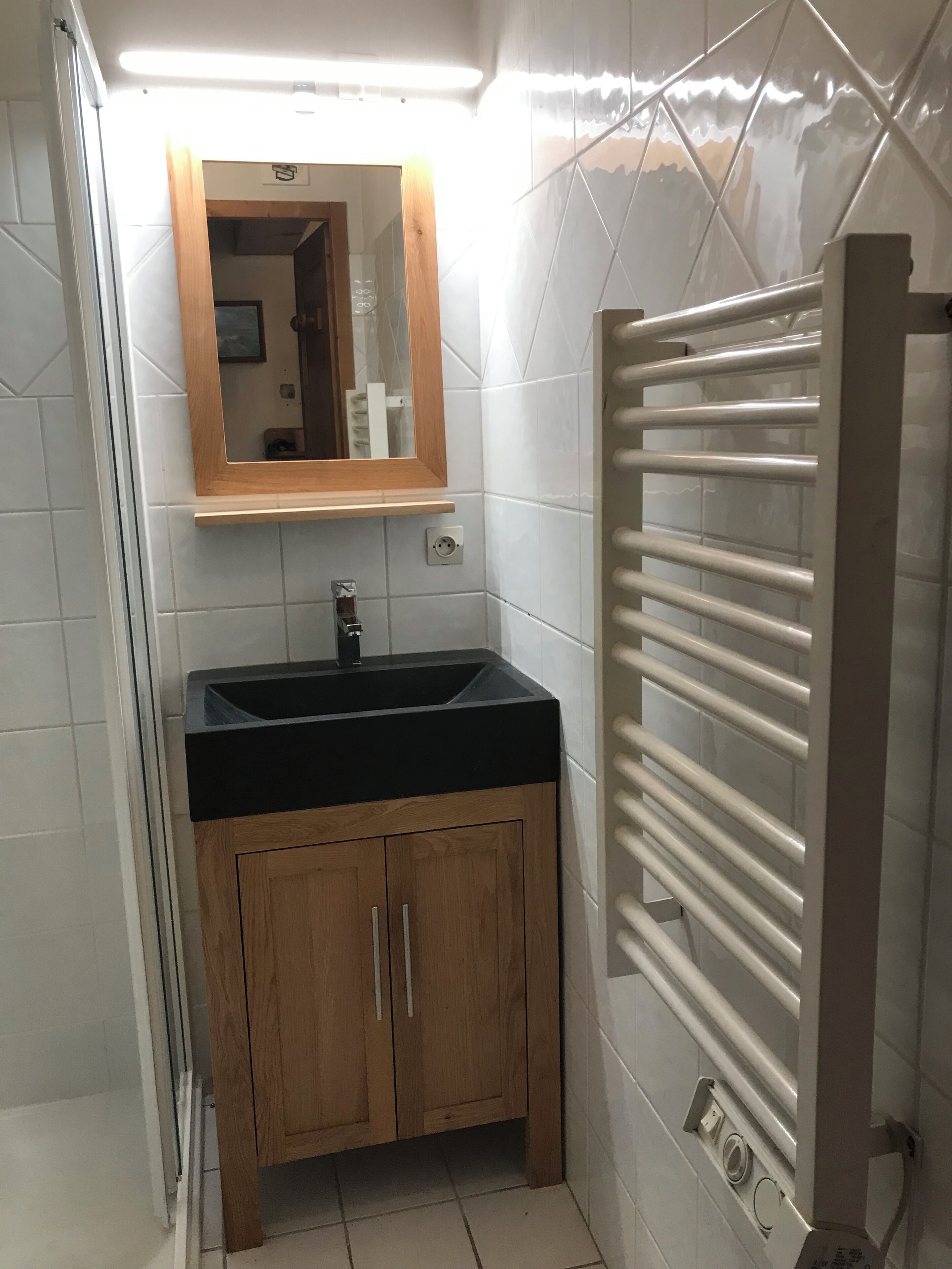 A bathroom with a black sink, wooden cabinets, a mirror, and a towel rack.