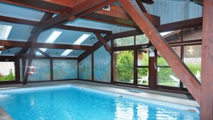 Une piscine intérieure avec des poutres en bois et de grandes fenêtres.