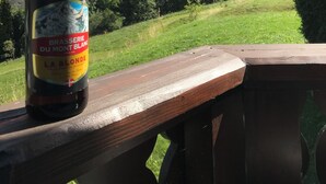 Une bouteille de bière La Blonde de la Brasserie du Mont Blanc, posée sur un banc en bois, avec une vue sur les montagnes en arrière-plan.