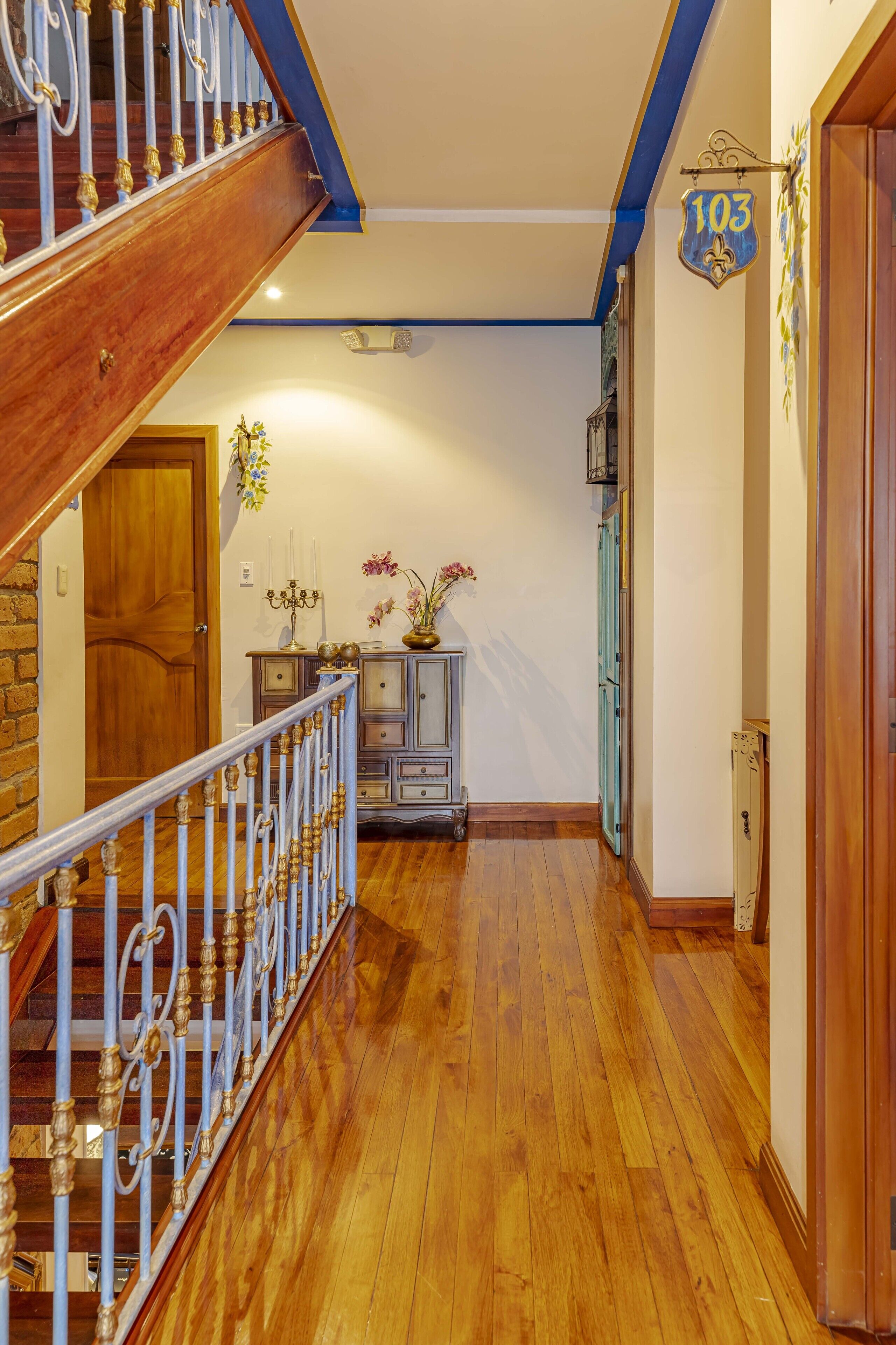A wooden staircase with a blue accent wall and a number sign indicating room 103.