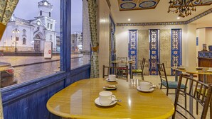 A dining area with a view of a historic building, ornate blue and white doors, and a chandelier. - Hotel Azul de la Plaza (Cuenca)