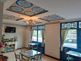 Un comedor con candelabro, techo estampado y ventanas con marco azul.