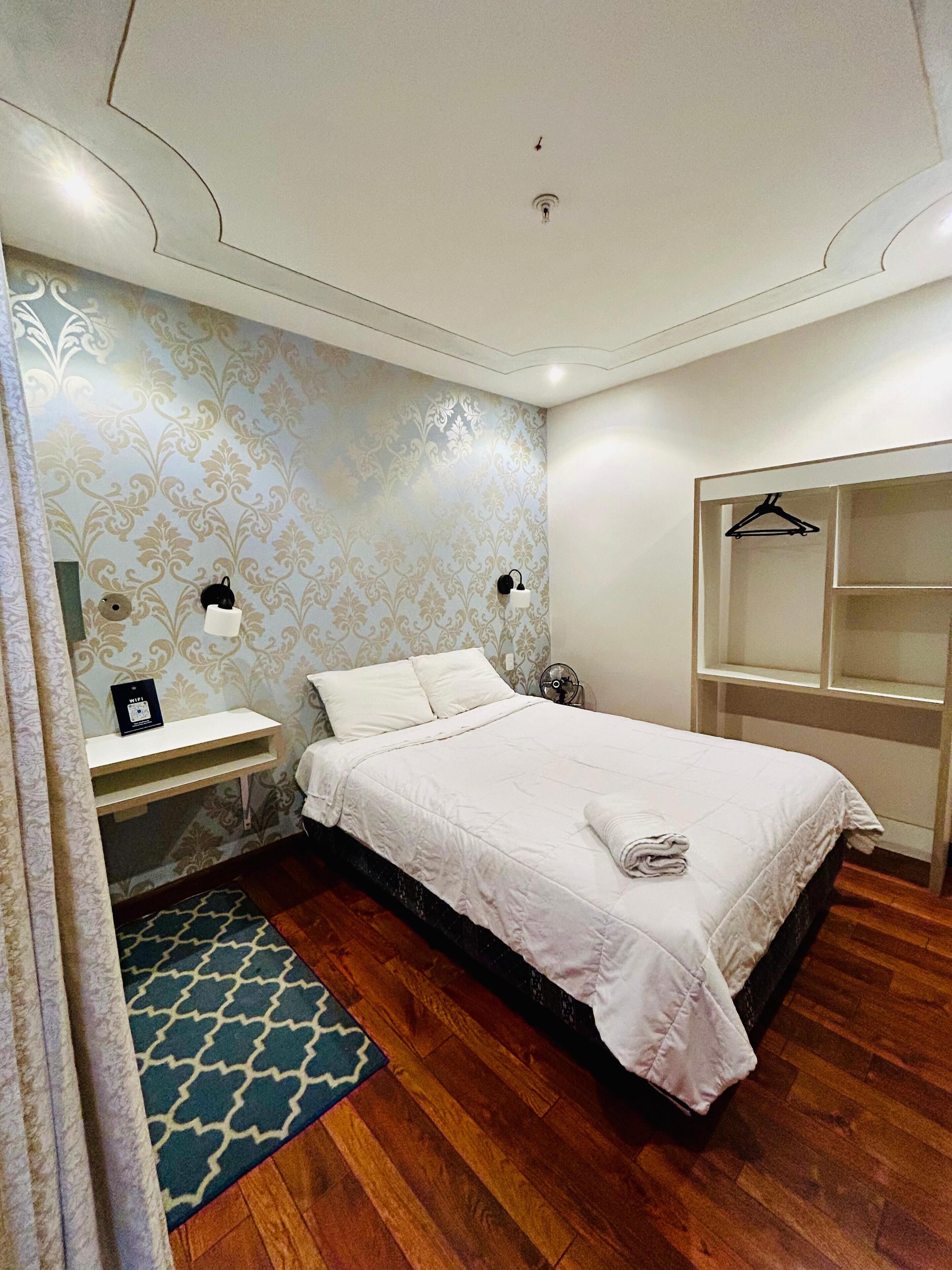 A neatly arranged bedroom with a bed, bedside table, and a wardrobe.