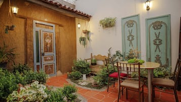 Un patio con puerta de madera, faroles colgantes y plantas en macetas.