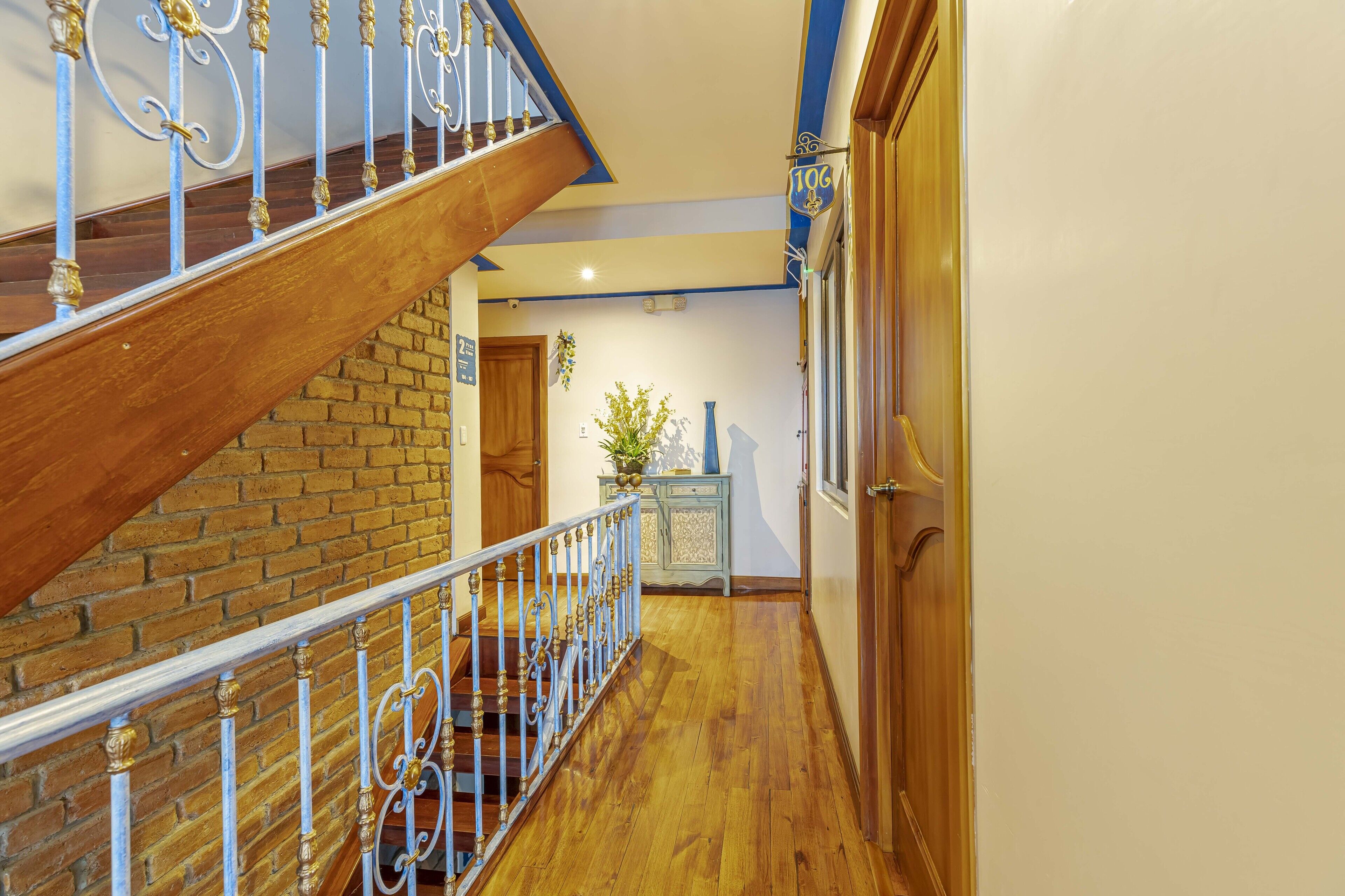 A wooden staircase with white balusters, a brick wall, and a wooden door.