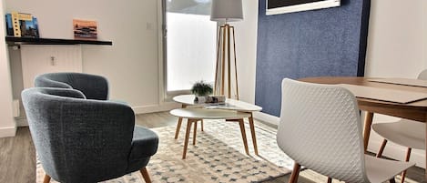 A modern living room with a round table, two armchairs, a floor lamp, and a bookshelf with books.