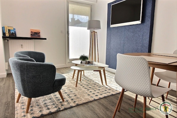 A modern living room with a round table, two armchairs, a floor lamp, and a bookshelf with books.