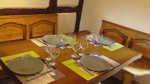 Une table à manger dressée avec des assiettes, des verres et des couverts, entourée de chaises en bois dotées d’assises rembourrées.