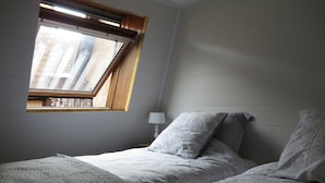 Une chambre à coucher avec un lit, une fenêtre et une table de chevet avec une lampe.