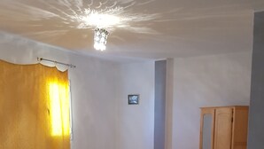 Un dormitori amb un llit, un armari de fusta, una petita catifes i una làmpada al sostre.
