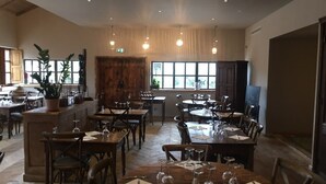 A restaurant with wooden tables and chairs, a bar area, and large windows providing natural light. - Modern villa with private pool between Bonifacio and Porto-vecchio (Figari)