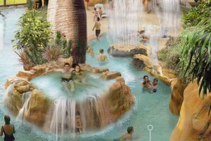 An indoor water park with multiple pools, waterfalls, and rock formations.