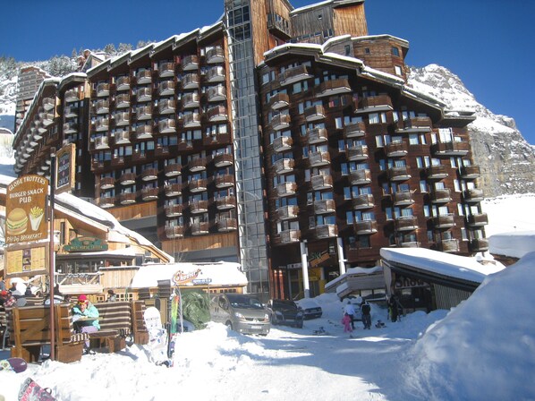 A large wooden hotel with multiple balconies and a ski lift visible in the background.
