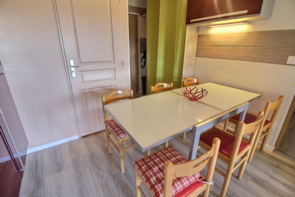 A dining area with a table and chairs, a bench, and a kitchen area with cabinets and a countertop.