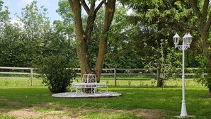 En park med en metalbænk, en lygtepæl og et indhegnet område.