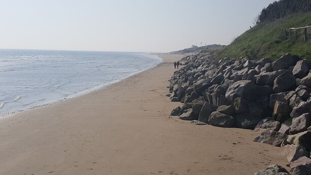 En strand med en klippefyldt kystlinje og krystalklart hav.