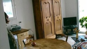Una habitación con un armario de madera, un televisor y una mesa de comedor.
