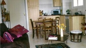 Un espacio habitable compacto con zona de comedor, kitchenette y sofá con cojines.