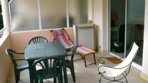 Un balcón con una mesa y sillas, una silla a rayas y una silla blanca.