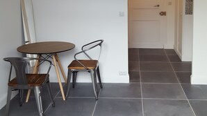 Een moderne keuken met een ronde tafel en twee stoelen, een witte deur en een betegelde vloer.